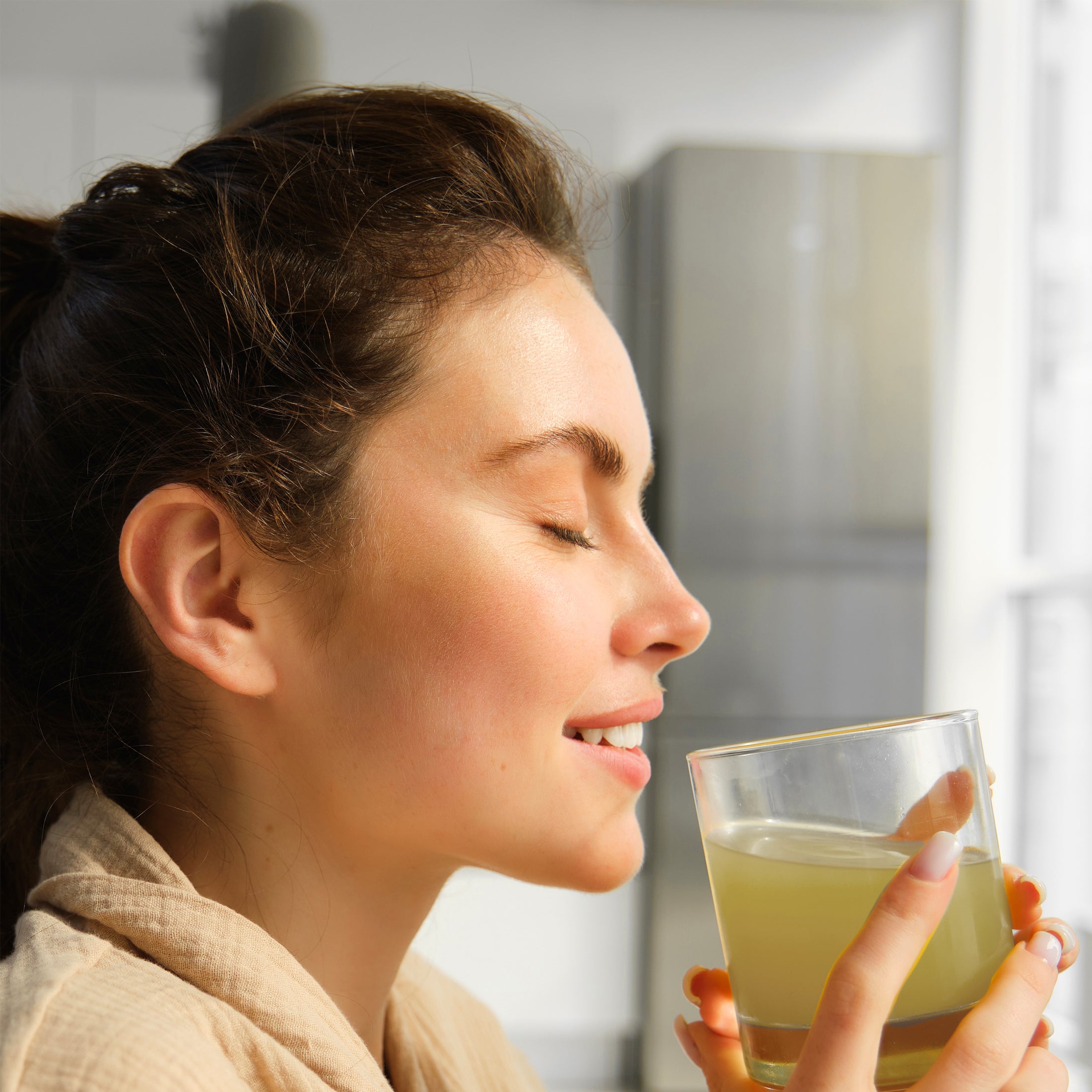 Woman drinking from a glass of lemonade in a kitchen setting