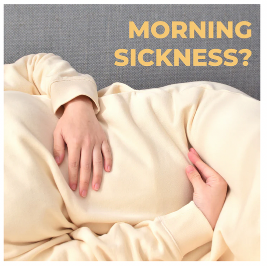 pregnant woman holding her belly laying down on couch, caption "morning sickness" 